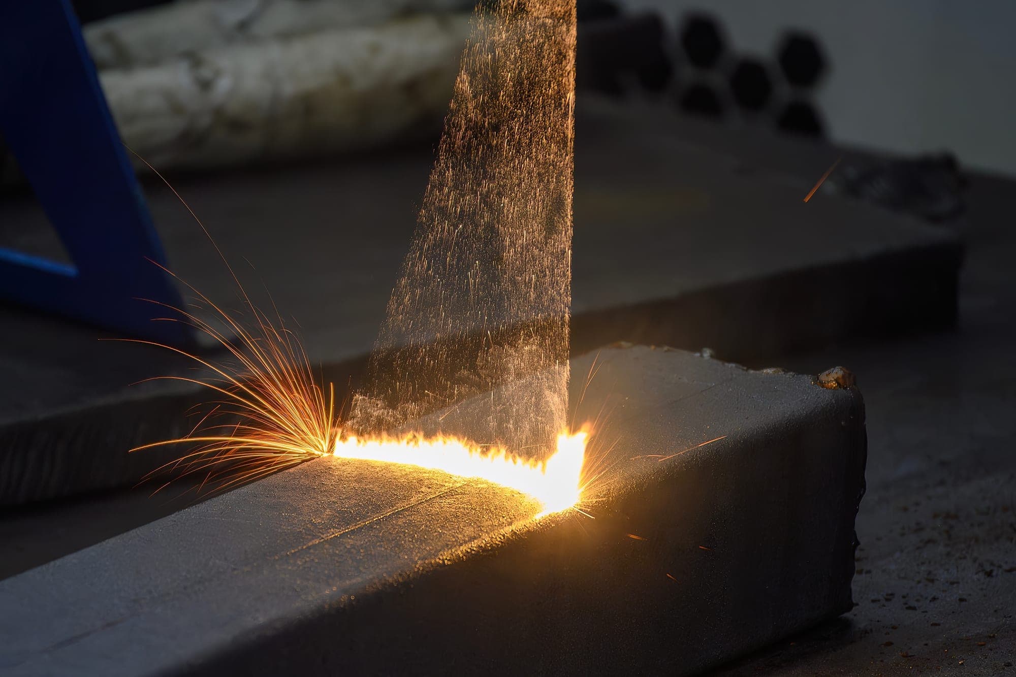 Laser cleaning throwing sparks as it strips coating from a steel beam
