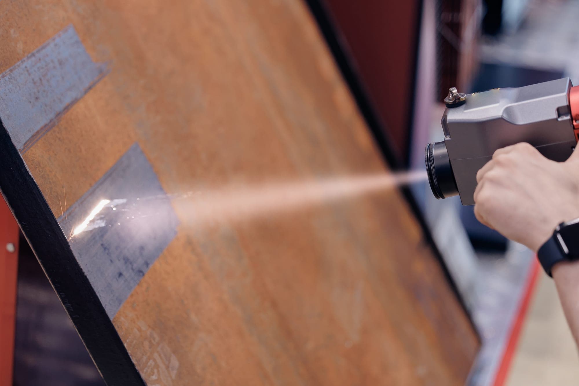 Laser cleaning gun stripping rust from a steel beam